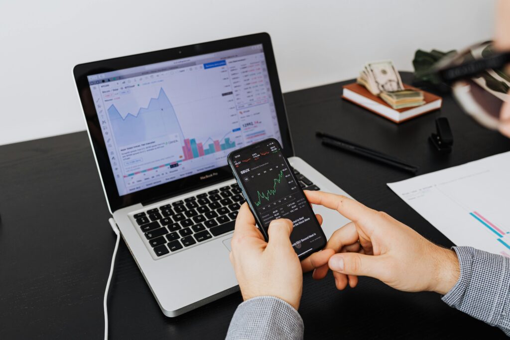 pexels-photo-5717758-5717758 Person analyzing stock market data on a laptop and smartphone indoors.